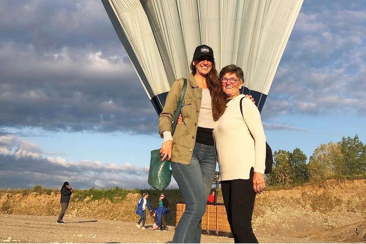 Sundance hot air balloon floating above green countryside at golden hour
